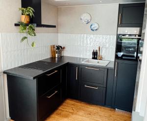 a kitchen with black cabinets and a sink at Naar de kust in Hollum