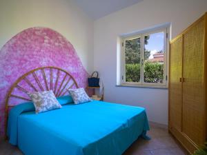 a bedroom with a blue bed with a pink headboard at Residence Olimpo in Capo Vaticano