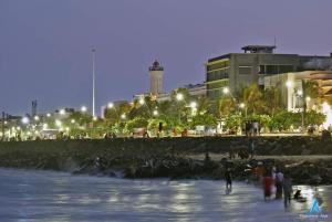 un grupo de personas caminando por la playa por la noche en Villa Betty Beach Front en Pondicherry