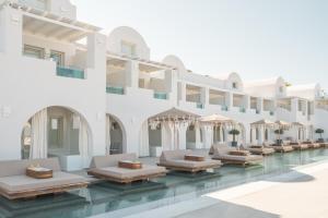 a pool with tables and umbrellas in a building at Apeiron Blue Santorini by Apeiron Hotels in Fira