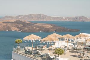 a resort with chairs and umbrellas and the water at Apeiron Blue Santorini - Sustainable Adult-Only Retreat in Fira