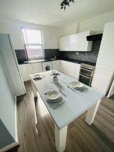a kitchen with a white table with plates and utensils on it at Stylish City Central Outskirts Sleeps 8 in Leeds