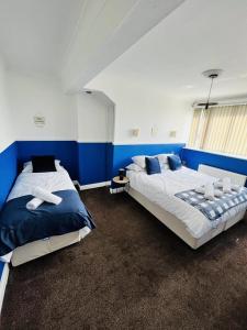 two beds in a bedroom with blue and white walls at Stylish City Central Outskirts Sleeps 8 in Leeds