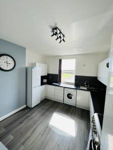 a kitchen with white appliances and a clock on the wall at Stylish City Central Outskirts Sleeps 8 in Leeds