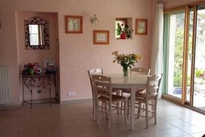 una mesa de comedor con sillas y un jarrón de flores en Gîte Léperon 2 en Clisson