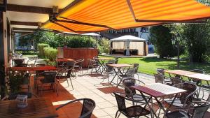 an outdoor patio with tables and chairs and an umbrella at Hardi's Hotel in Inzell