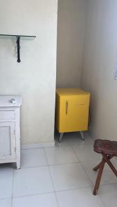 un meuble jaune dans une pièce blanche avec un tabouret dans l'établissement Casa Siulan, à Porto de Galinhas