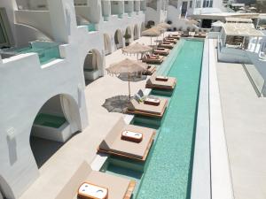 una piscina a sfioro con tavoli e ombrelloni in un resort di Apeiron Blue Santorini - Sustainable Adults Only 14 Plus a Firà