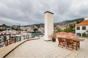 um pátio com uma mesa e cadeiras numa varanda em A ver o mar rooms- Funchal city center no Funchal
