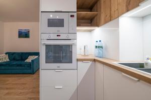 uma cozinha com armários brancos e um forno com placa de fogão em Apartament Ali-Leo em Gdynia