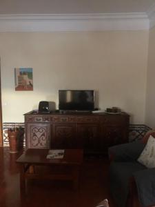 una sala de estar con TV de pantalla plana en un armario de madera en Maria Guest house, en Albufeira