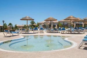 una piscina con sillas, mesas y sombrillas en Algarve Luxury Apartment in Boavista Golf Resort, en Lagos