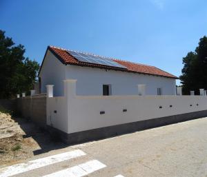 Un edificio blanco con una valla al lado de una carretera. en Holiday house Parancin, en Stankovci