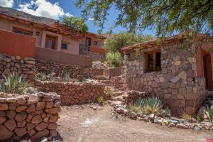 a house with a stone wall next to a building at CasaCalma Hotel Boutique in Tilcara