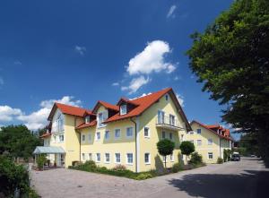 a large yellow house with red roofs on a street at Hotel Nummerhof in Erding