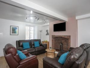 a living room with leather furniture and a fireplace at Maes Y Ffynnon in Pwllheli