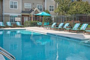 a swimming pool with lounge chairs and an umbrella at Sonesta ES Suites Raleigh Durham Airport Morrisville in Morrisville