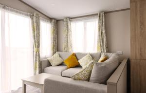 a living room with a gray couch with yellow pillows at TILLINGHAM CARAVAN 3 bed 2 bath caravan. in Great Clacton