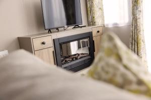 a living room with a fireplace and a tv at TILLINGHAM CARAVAN 3 bed 2 bath caravan. in Great Clacton