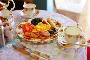 ein Frühstücksteller auf einem Tisch mit zwei Tassen in der Unterkunft The Evergreen Inn in Banbury