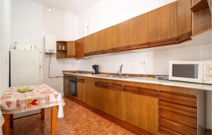 cocina con armarios de madera y microondas en 3 Bedroom Amazing Home In El Campillo, en El Campillo