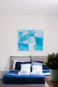 uma cama azul com almofadas brancas e um quadro na parede em The Secret Garden em Salerno mais 67 fotografias