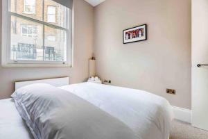 a white bedroom with a bed and a window at Hampstead High Flyer in London