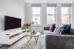 a living room with a couch and a flat screen tv at Hampstead High Flyer in London