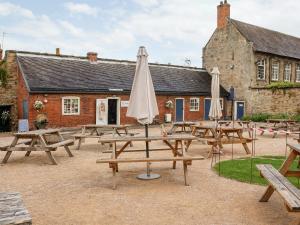 a group of wooden picnic tables with an umbrella at Tithe Barn in Derby