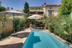 a swimming pool in a backyard with an umbrella at Le Castel de Castillon - Maison d'exception à 10 minutes de Saint Emilion in Castillon-la-Bataille