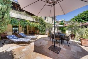 a patio with a table and chairs and an umbrella at Le Castel de Castillon - Maison d'exception à 10 minutes de Saint Emilion in Castillon-la-Bataille