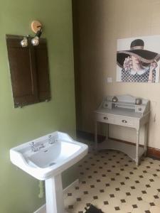 ein Badezimmer mit einem weißen Waschbecken und einem Tisch in der Unterkunft L’Annexe in Auxi-le-Château