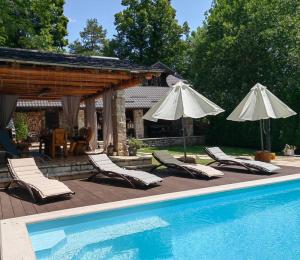 a swimming pool with lounge chairs and umbrellas next to a swimming pool at Luxury Chalet Regina in Bruvno