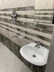 a white sink in a bathroom with striped walls at Variyar Service Apartments Unit E 2nd Floor in Vellore