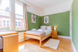 a bedroom with a bed with green walls and a window at Monthly Discounts,10 Guests, Business in Leicester