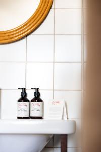 - une salle de bains avec 2 bouteilles de savon sur un lavabo dans l'établissement Hôtel Cabane - Orso Hotels, à Paris