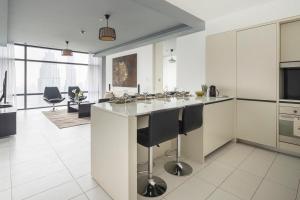 a kitchen with a large island with black bar stools at Frank Porter - Index Tower in Dubai