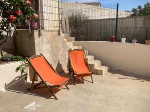 twee oranje stoelen naast een trap bij Petite maison avec terrasse et piscine in Beaucaire