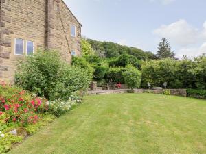 a garden with a brick building and flowers at Fern Cottage in Bakewell