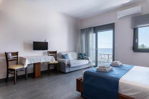 Pokój hotelowy z łóżkiem, biurkiem i kanapą w obiekcie Long Beach Resort w Jerapetrze