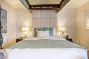 The Swan Hotel, Wells, Somerset في ويلْزْ: غرفة نوم بسرير كبير فيها مصباحين