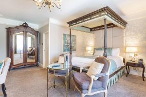 1 dormitorio con cama con dosel, mesa y sillas en The Swan Hotel, Wells, Somerset, en Wells