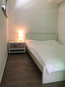 - une petite chambre avec un lit blanc et une lampe dans l'établissement Zentrale Ferienwohnung mit Waldblick, à Hofstetten
