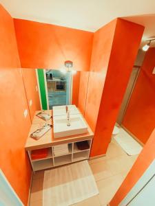 La salle de bains orange est pourvue d'un lavabo et d'un miroir. dans l'établissement Zentrale Ferienwohnung mit Waldblick, à Hofstetten