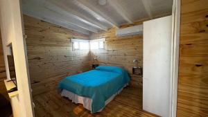 1 dormitorio con 1 cama en una pared de madera en El pisito en San Rafael