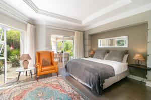 a bedroom with a bed and an orange chair at BS1 - Pezula Exclusive Elegance in Knysna +26 photos