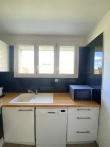 a kitchen with a sink and two windows at Port Marianne City Cosy Apparemment in Montpellier