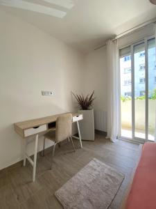 a desk and a chair in a room with a window at Port Marianne City Cosy Apparemment in Montpellier