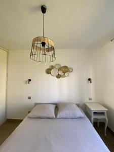 a bedroom with a white bed and a chandelier at Port Marianne City Cosy Apparemment in Montpellier