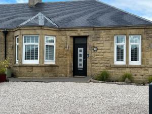 a stone house with a black door at Luxury 2 Bedroom Cottage in West Calder